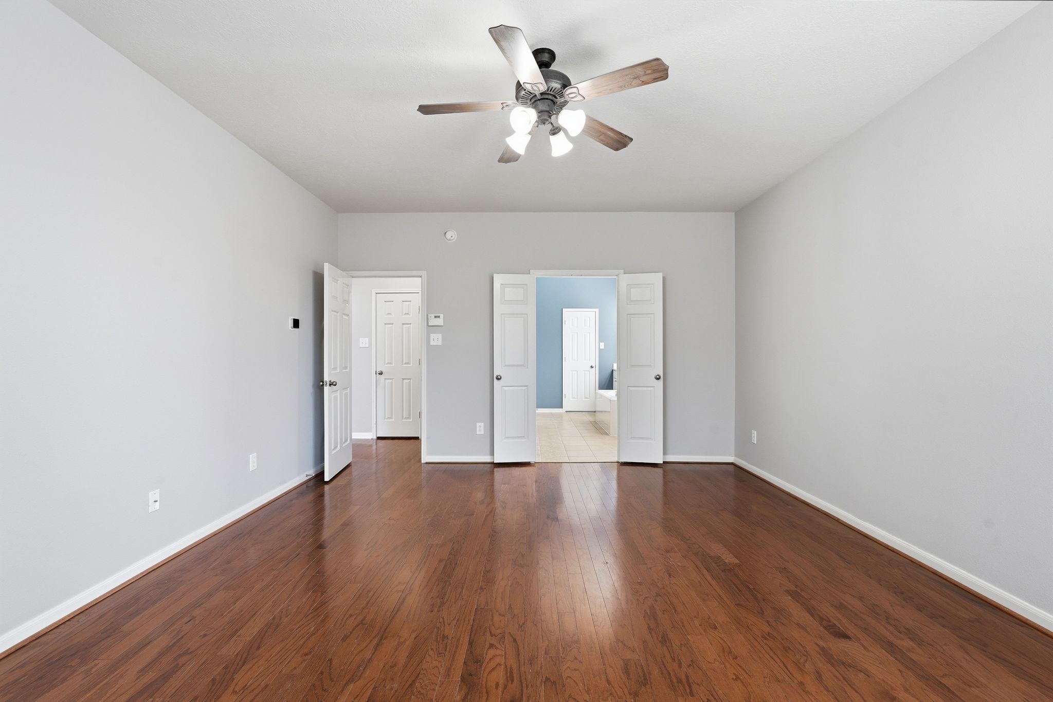 24931 Corbin Gate Drive Spring, TX 77389 - Photo 32 of 50 This spacious primary bedroom features hardwood floors, neutral walls, and a ceiling fan. It includes double doors leading to the primary bathroom.