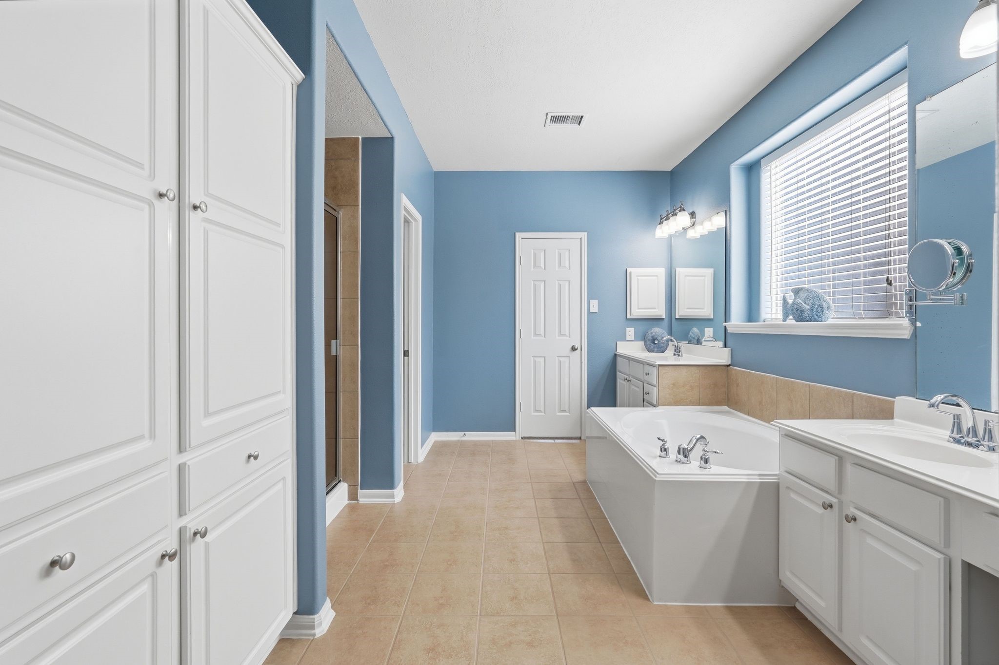 24931 Corbin Gate Drive Spring, TX 77389 - Photo 34 of 50 This primary bathroom features a spacious layout, a large soaking tub, dual sinks, and ample cabinet storage. Natural light streams in creating a bright and inviting atmosphere.