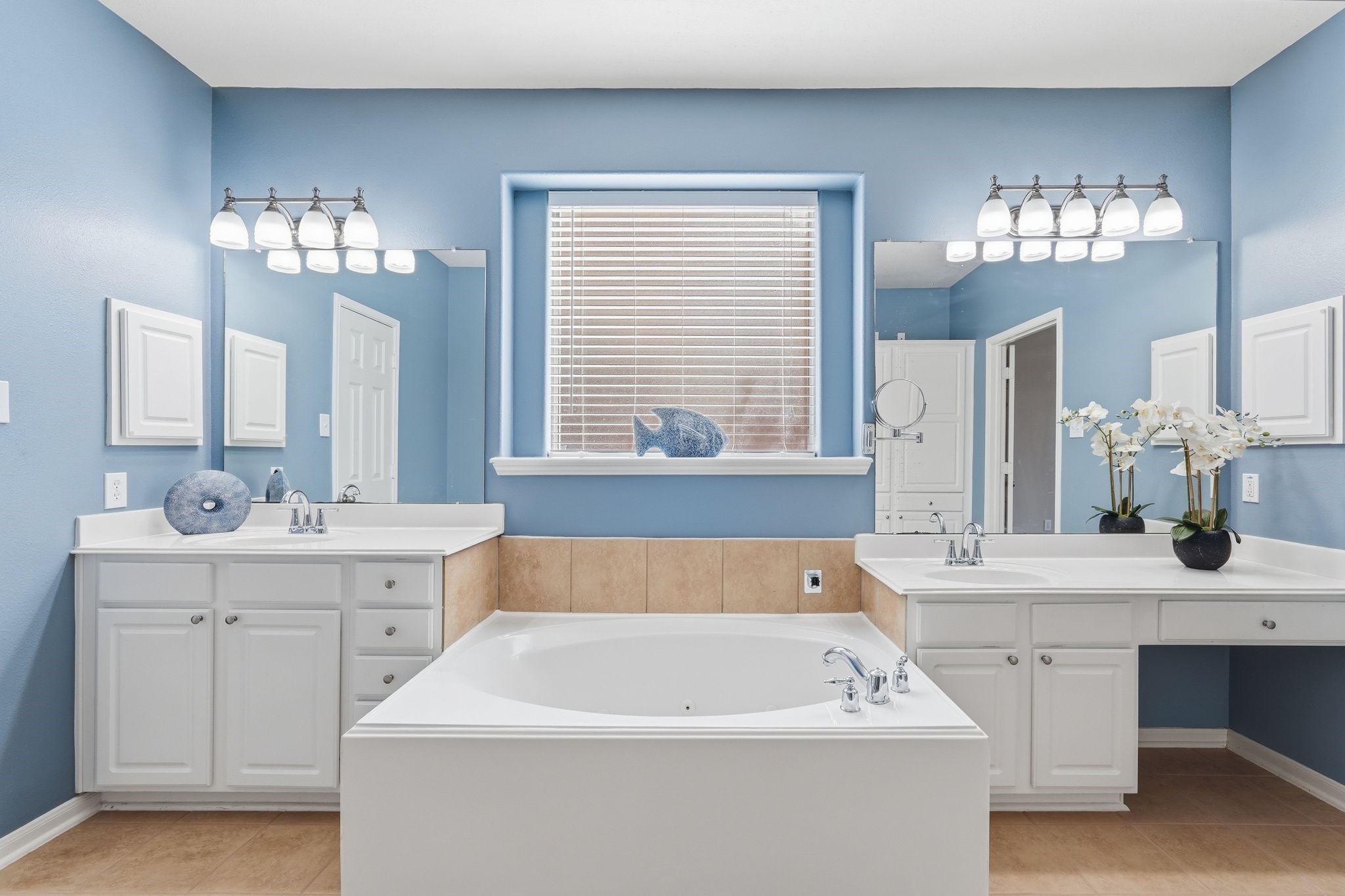 24931 Corbin Gate Drive Spring, TX 77389 - Photo 36 of 50 This primary bathroom features a soothing blue color scheme with ample natural light. It includes a soaking tub, dual vanities, modern light fixtures, and elegant white cabinetry, creating a serene and functional space.
