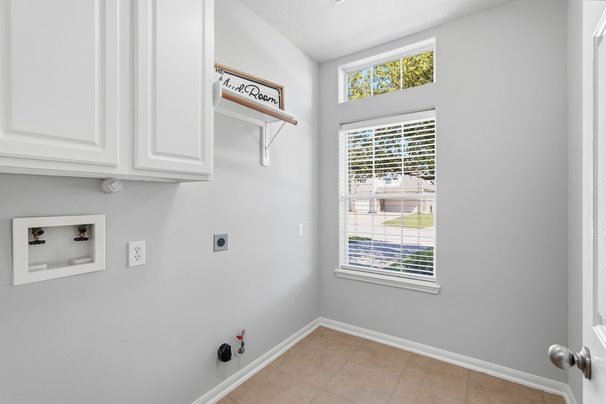 24931 Corbin Gate Drive Spring, TX 77389 - Photo 46 of 50 Bright laundry room with neutral-toned tiles, white cabinetry, and a window offering natural light. Hookups for washer and dryer are ready.