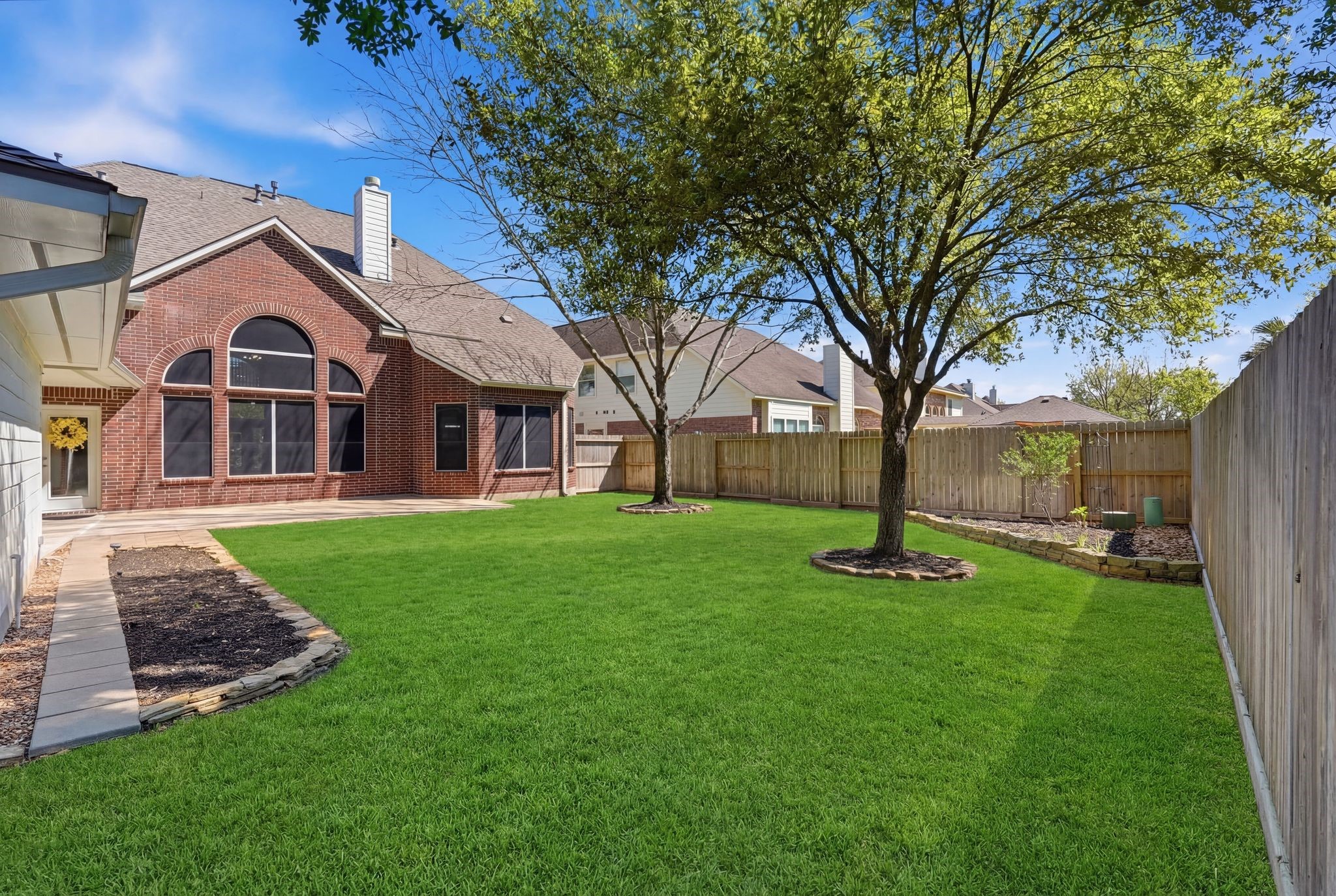 24931 Corbin Gate Drive Spring, TX 77389 - Photo 48 of 50 Spacious, well-maintained backyard with lush green grass, a mature tree, and a charming brick exterior. Ideal for outdoor activities and relaxation. Plenty of room for a pool!