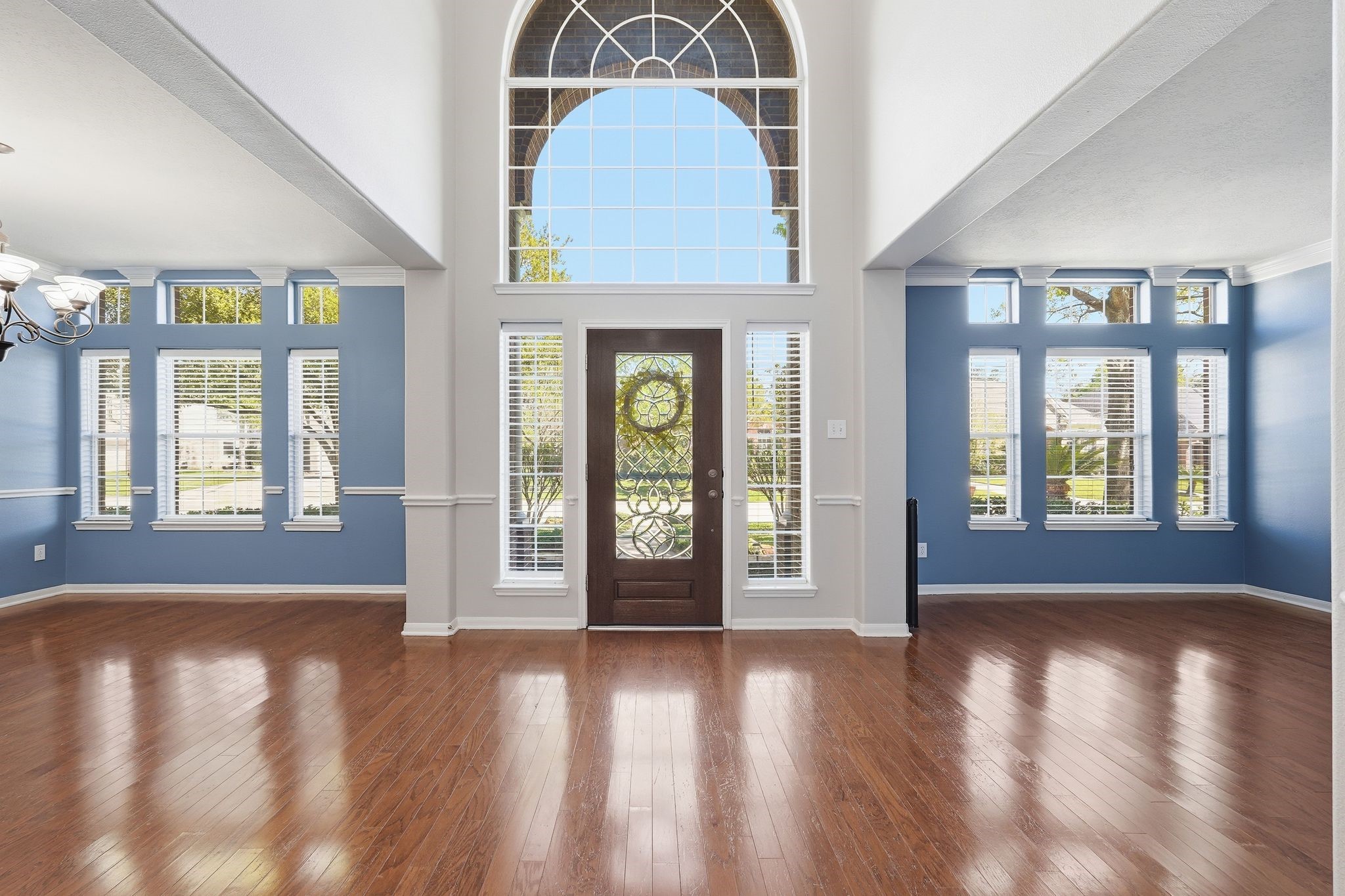 24931 Corbin Gate Drive Spring, TX 77389 - Photo 8 of 50 This spacious entryway features high ceilings and abundant natural light from large windows, complementing the elegant hardwood floors. The intricate design on the front door adds a touch of sophistication.