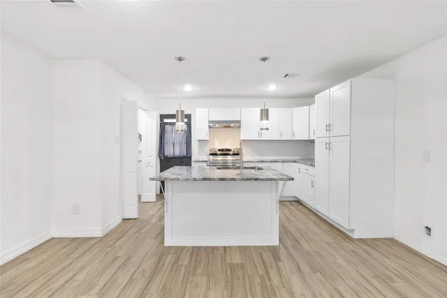 a kitchen with kitchen island a sink a stove a refrigerator and white cabinets