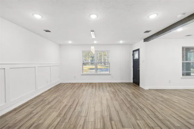 an empty room with wooden floor and windows