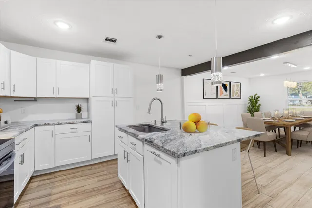 a kitchen with granite countertop a white stove top oven and white cabinets with wooden floor