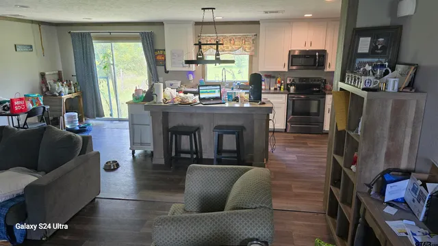 a living room with stainless steel appliances furniture a fireplace a flat screen tv and a window