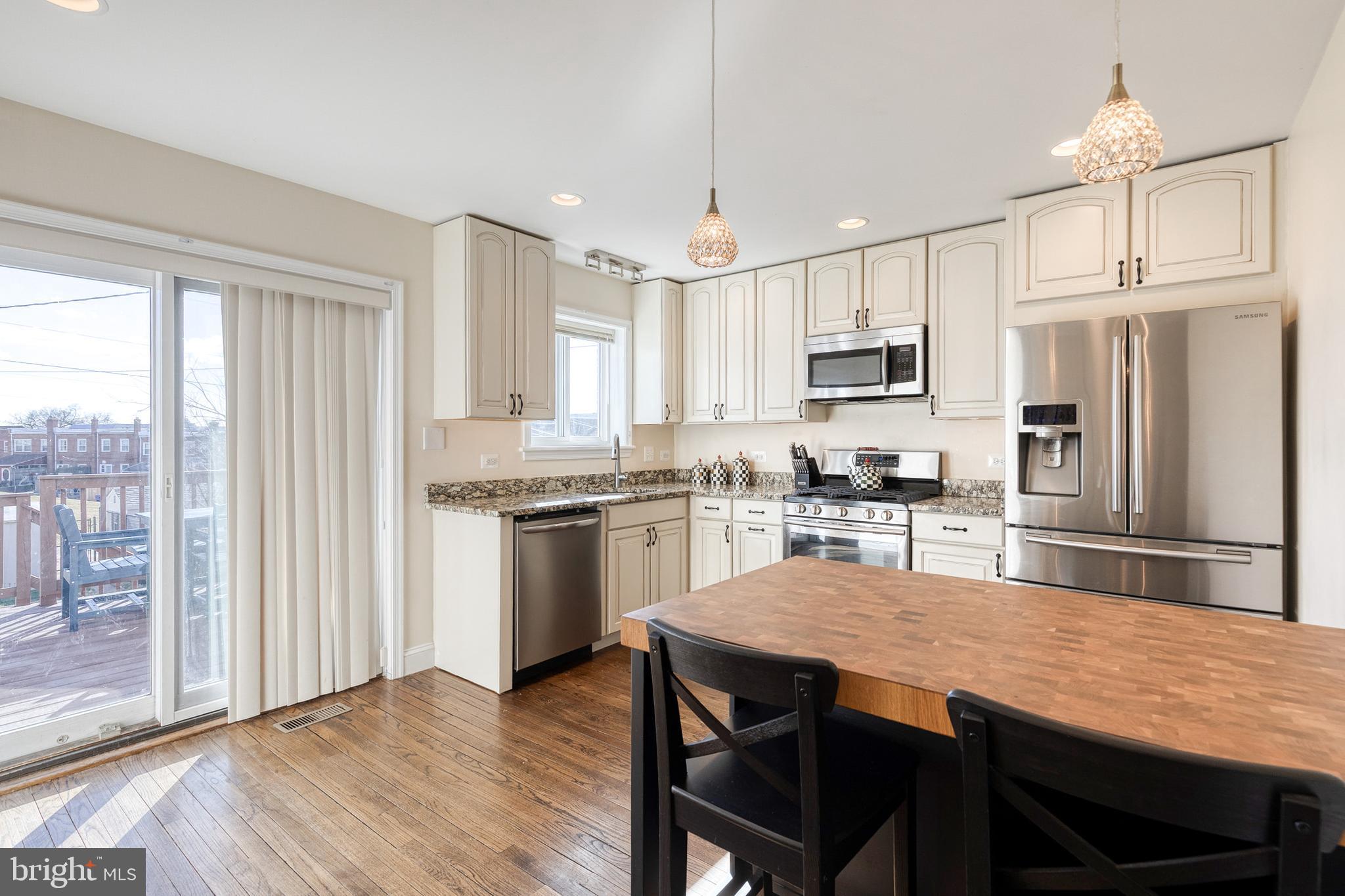 1205 Roland Heights Avenue Baltimore, MD 21211 - Photo 8 of 36 a kitchen with stainless steel appliances granite countertop a stove a refrigerator a sink dishwasher a dining table and chairs with wooden floor