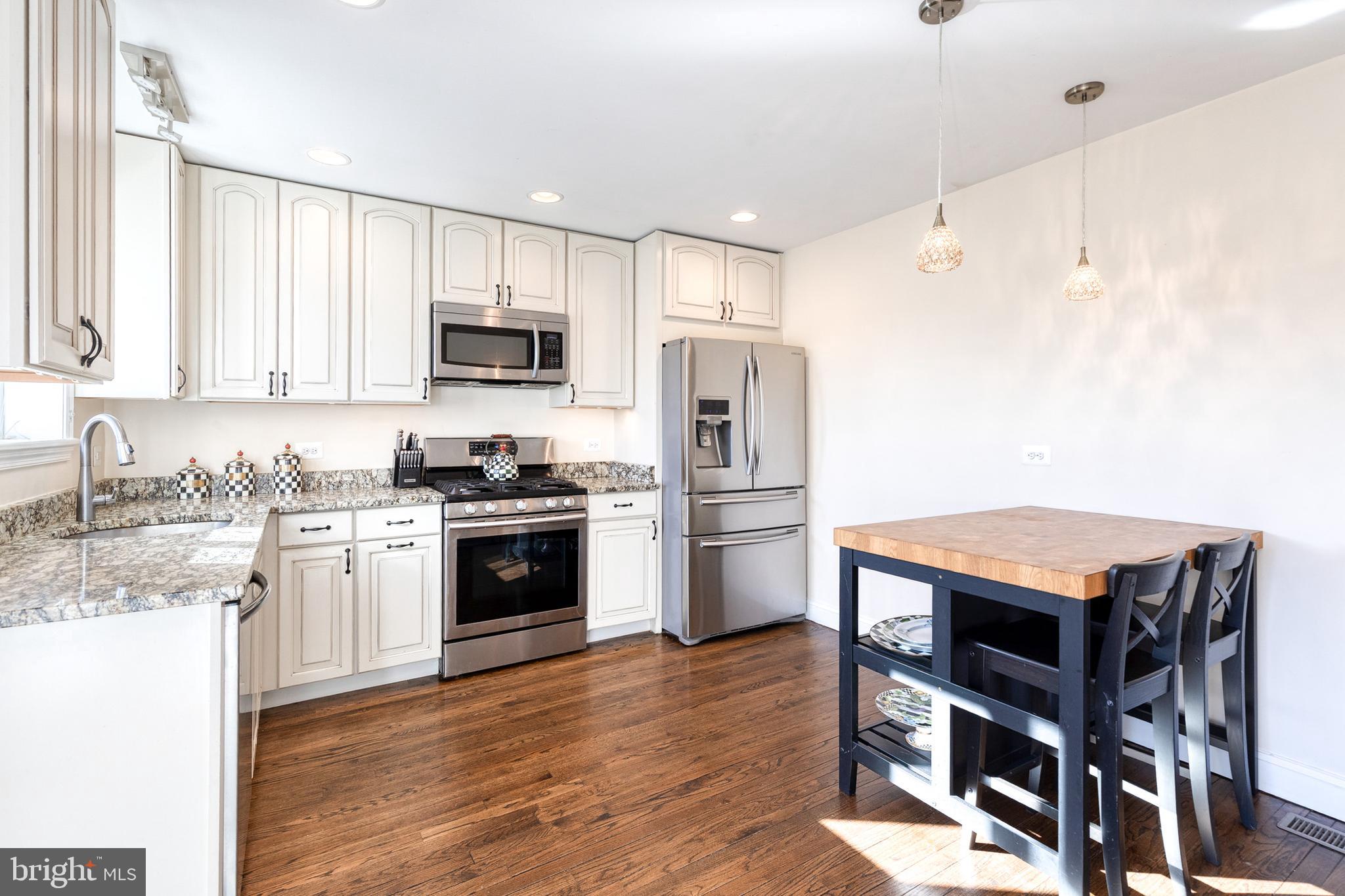 1205 Roland Heights Avenue Baltimore, MD 21211 - Photo 9 of 36 a kitchen with stainless steel appliances granite countertop a stove top oven a sink dishwasher and a refrigerator with wooden floor