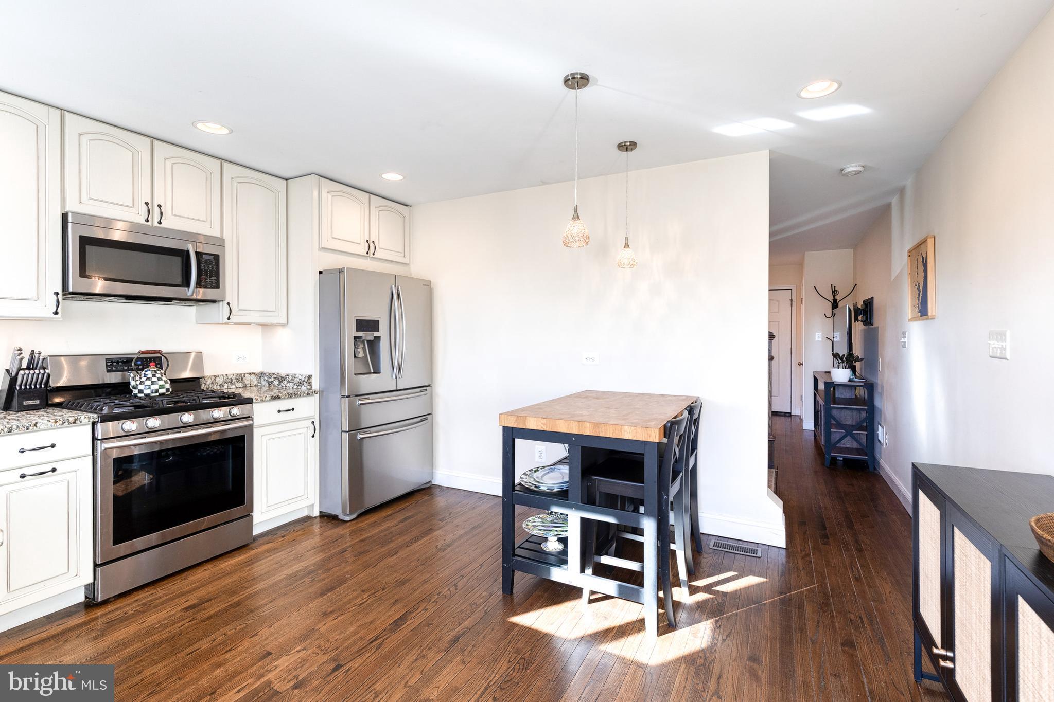 1205 Roland Heights Avenue Baltimore, MD 21211 - Photo 10 of 36 a kitchen with stainless steel appliances a stove a refrigerator and a microwave oven with wooden floor