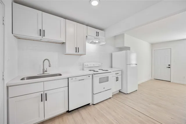 a kitchen with white cabinets white stainless steel appliances and sink