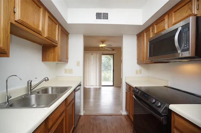 a kitchen with stainless steel appliances granite countertop a sink a microwave cabinets and wooden floor