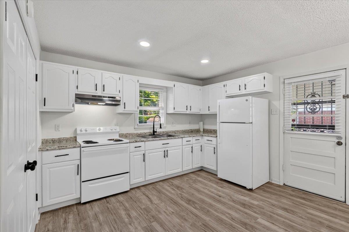 2717 Merle Street Memphis, TN 38118 - Photo 3 of 18 Modern kitchen featuring white cabinetry, granite-style countertops, stainless steel sink with a matte black faucet, recessed lighting, and wood-finish flooring