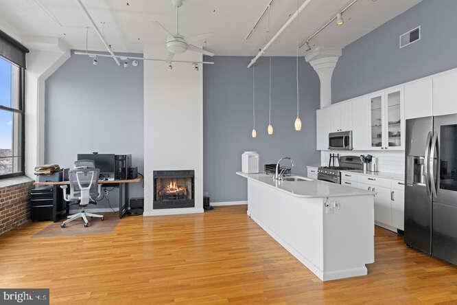 314 North 12th Street, Unit 1004 Philadelphia, PA 19107 - Photo 9 of 16 a large white kitchen with cabinets a sink a stove a refrigerator and a fireplace
