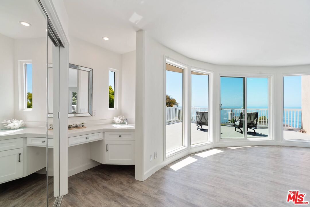 31518 Broad Beach Road Malibu, CA 90265 - Photo 16 of 27 a large white kitchen with stainless steel appliances a large counter top a sink and a large window