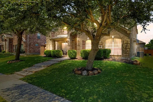 a front view of a house with a garden and tree