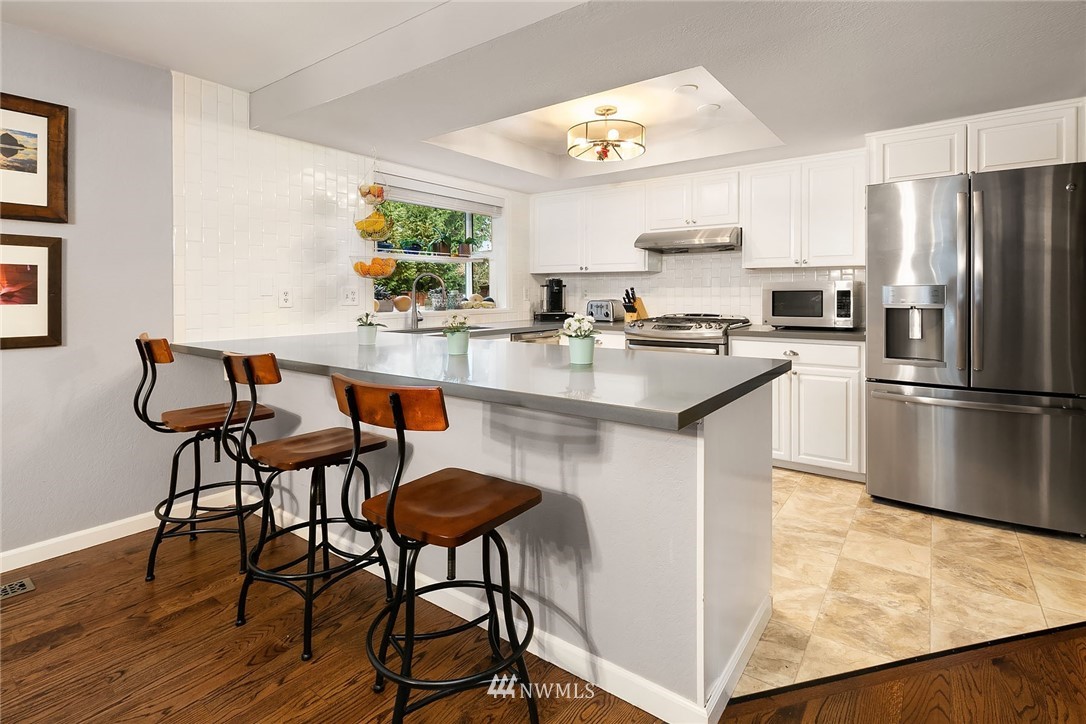 18207 Southeast 147th Street Renton, WA 98059 - Photo 6 of 23 a kitchen with stainless steel appliances granite countertop a table chairs stove and refrigerator