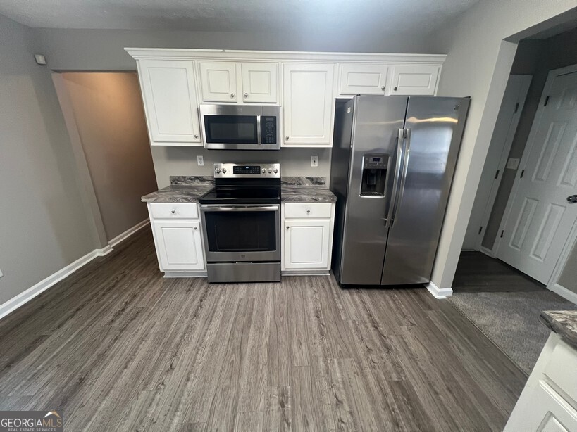 70 Princeton Way Covington, GA 30016 - Photo 9 of 32 a kitchen with stainless steel appliances a refrigerator microwave and stove