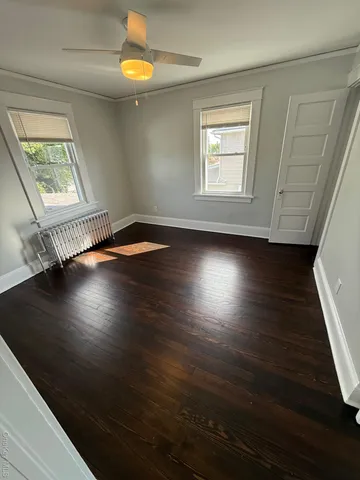 an empty room with wooden floor cabinet and windows