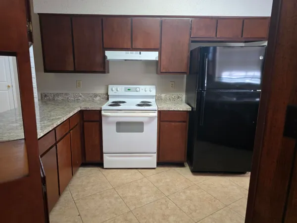 an empty room with a chandelier fan and windows
