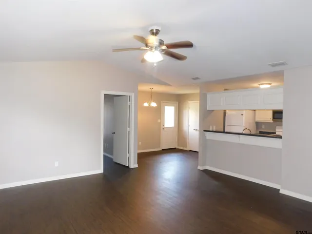 a view of an empty room with window and wooden floor