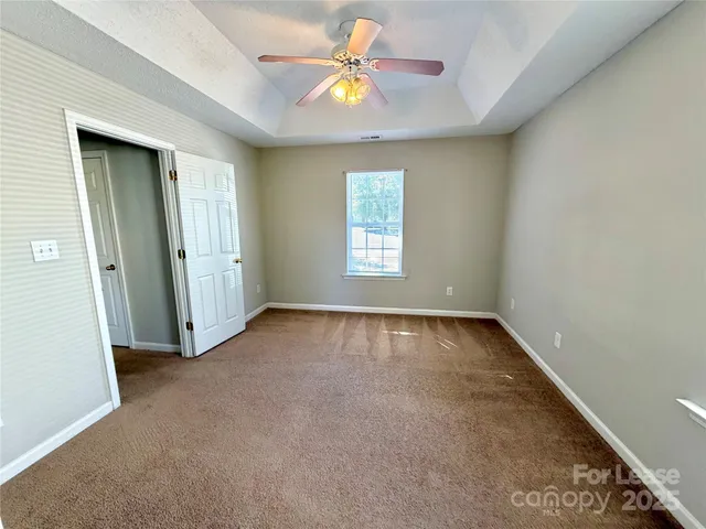 an empty room with windows and chandelier fan