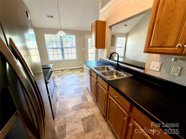 a kitchen with granite countertop a sink stove and refrigerator