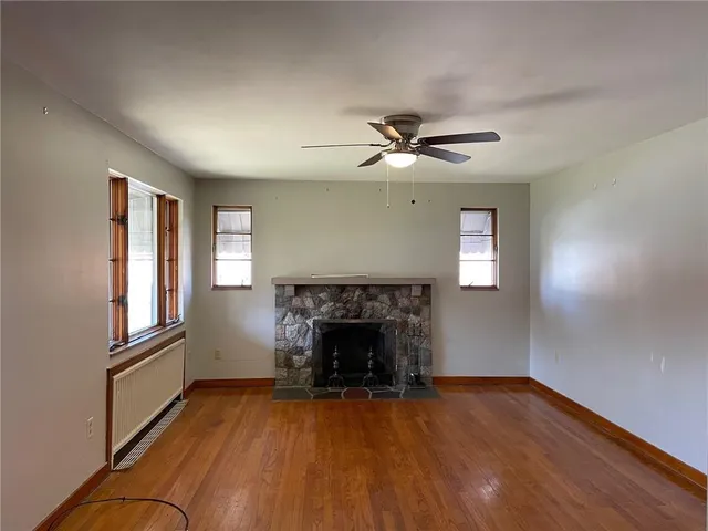 an empty room with windows fireplace and wooden floor