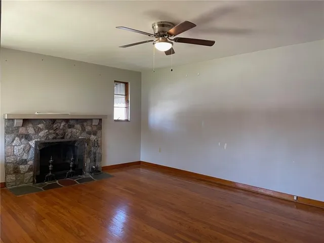 an empty room with wooden floor fireplace and windows