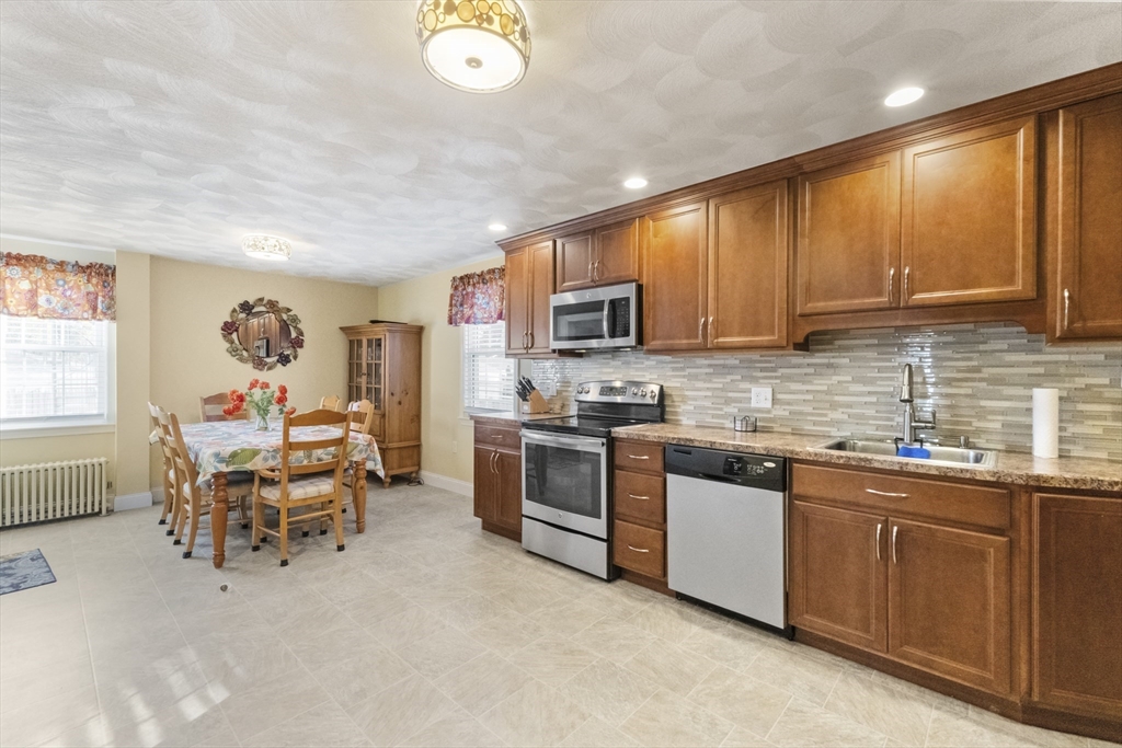 36 Forest Street Peabody, MA 01960 - Photo 12 of 35 a kitchen with stainless steel appliances granite countertop a stove top oven a sink dishwasher a dining table and chairs with wooden floor