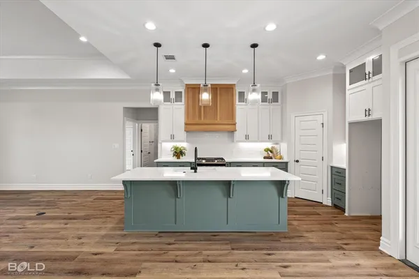 a kitchen with kitchen island stainless steel appliances a sink cabinets and wooden floor