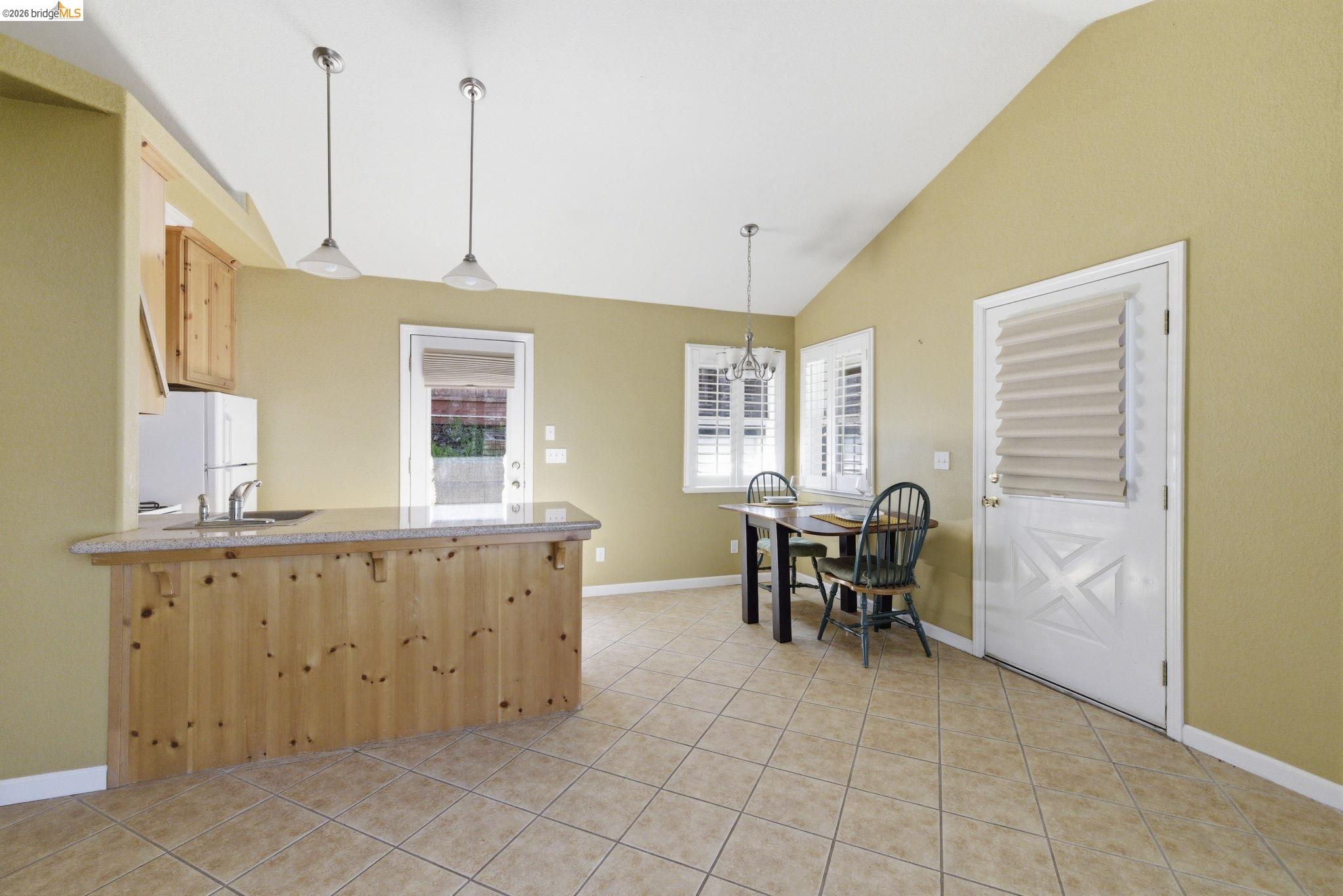 18389 Woodham Carne Road Sonora, CA 95370 - Photo 23 of 29 Kitchen featuring light wood finish cabinets, lofted ceiling, freestanding refrigerator, light tile patterned floors, and a peninsula
