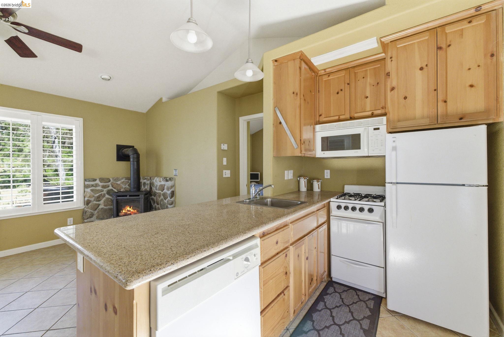 18389 Woodham Carne Road Sonora, CA 95370 - Photo 25 of 29 Kitchen with white appliances, light wood finish cabinets, light tile patterned flooring, a peninsula, and vaulted ceiling