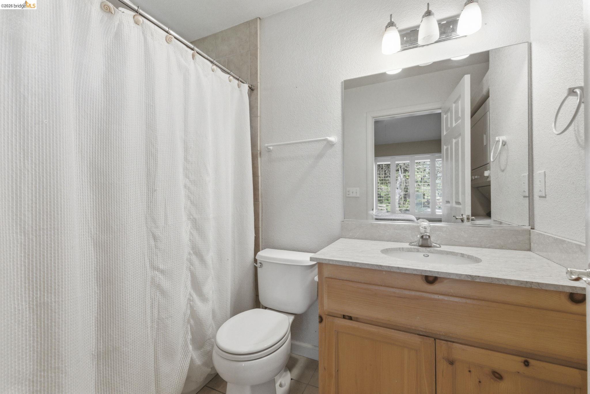 18389 Woodham Carne Road Sonora, CA 95370 - Photo 26 of 29 Full bath featuring a textured wall, curtained shower, vanity, and light tile patterned flooring