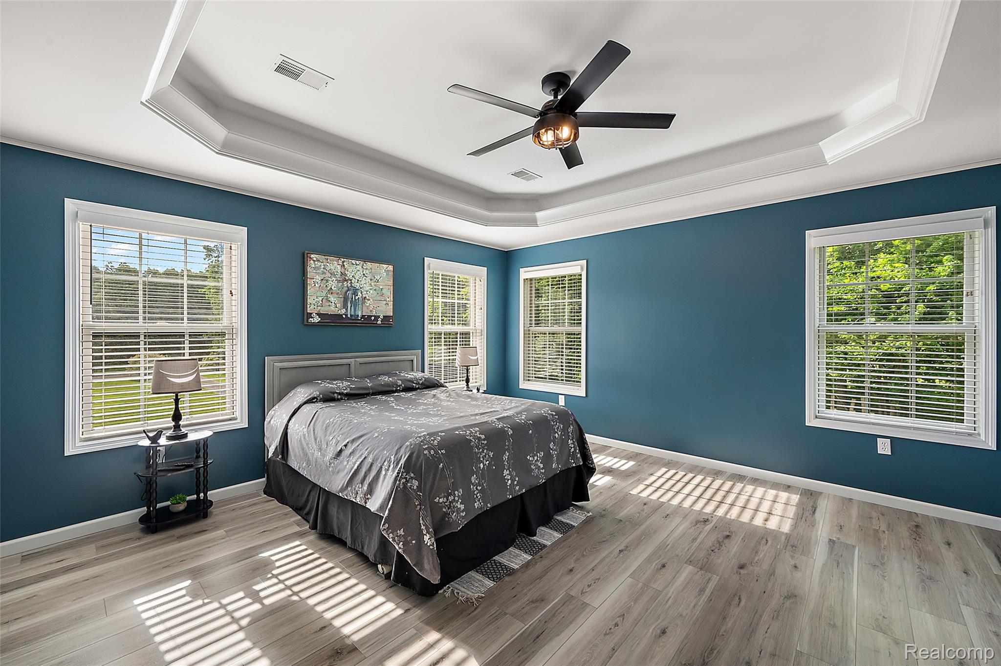 5035 Hidden Ridge Road Metamora, MI 48455 - Photo 28 of 65 Bedroom featuring a tray ceiling with crown molding, a ceiling fan with integrated lighting, wood-finish flooring, and multiple windows