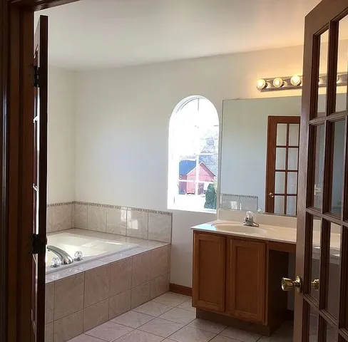 a bathroom with a tub sink and mirror