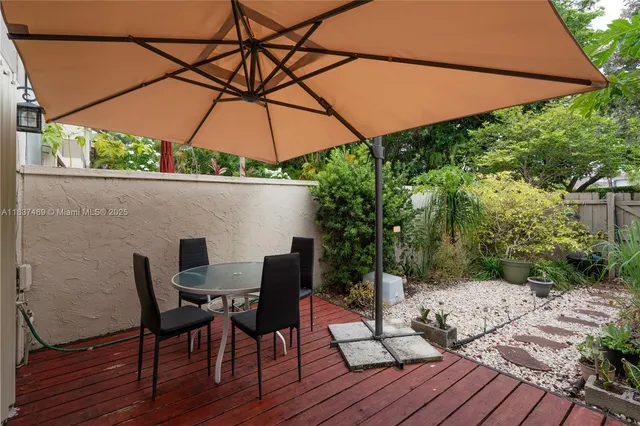 a patio with wooden floor a yard a table and chairs under an umbrella