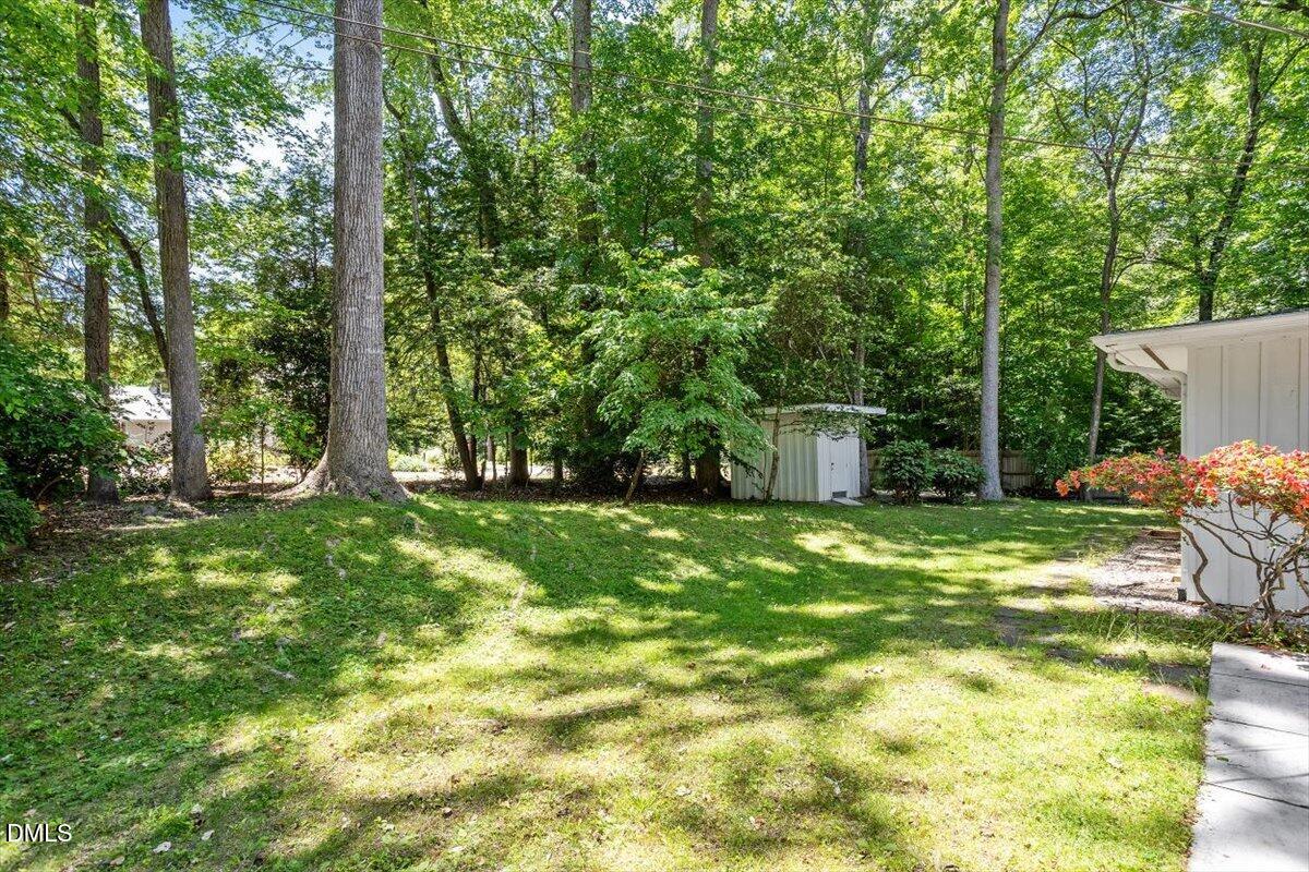 904 Kings Mill Road Chapel Hill, NC 27517 - Photo 30 of 33 a backyard of a house with table and chairs plants and large trees