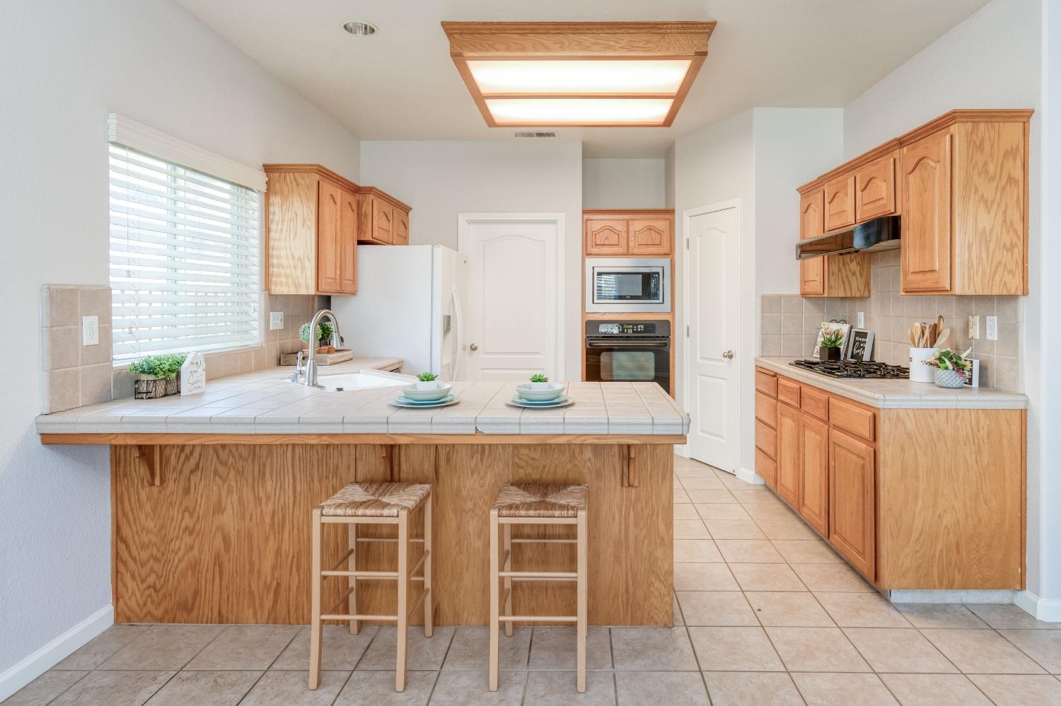 6580 East Raco Avenue Fresno, CA 93727 - Photo 12 of 30 a kitchen with stainless steel appliances kitchen island granite countertop a table chairs sink and cabinets