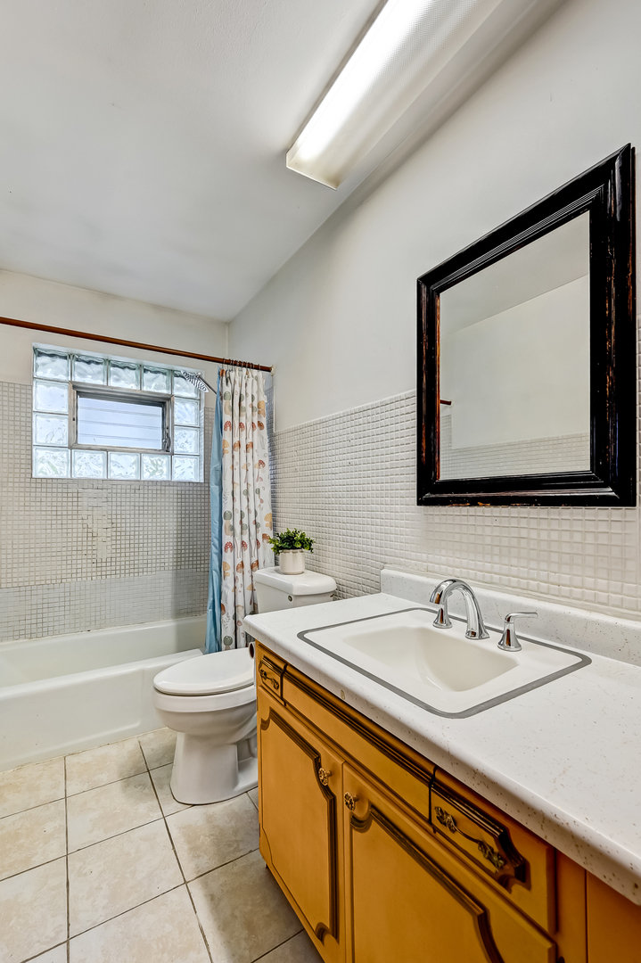 219 79th Street Burr Ridge, IL 60527 - Photo 13 of 28 a bathroom with a sink a toilet a mirror and bathtub