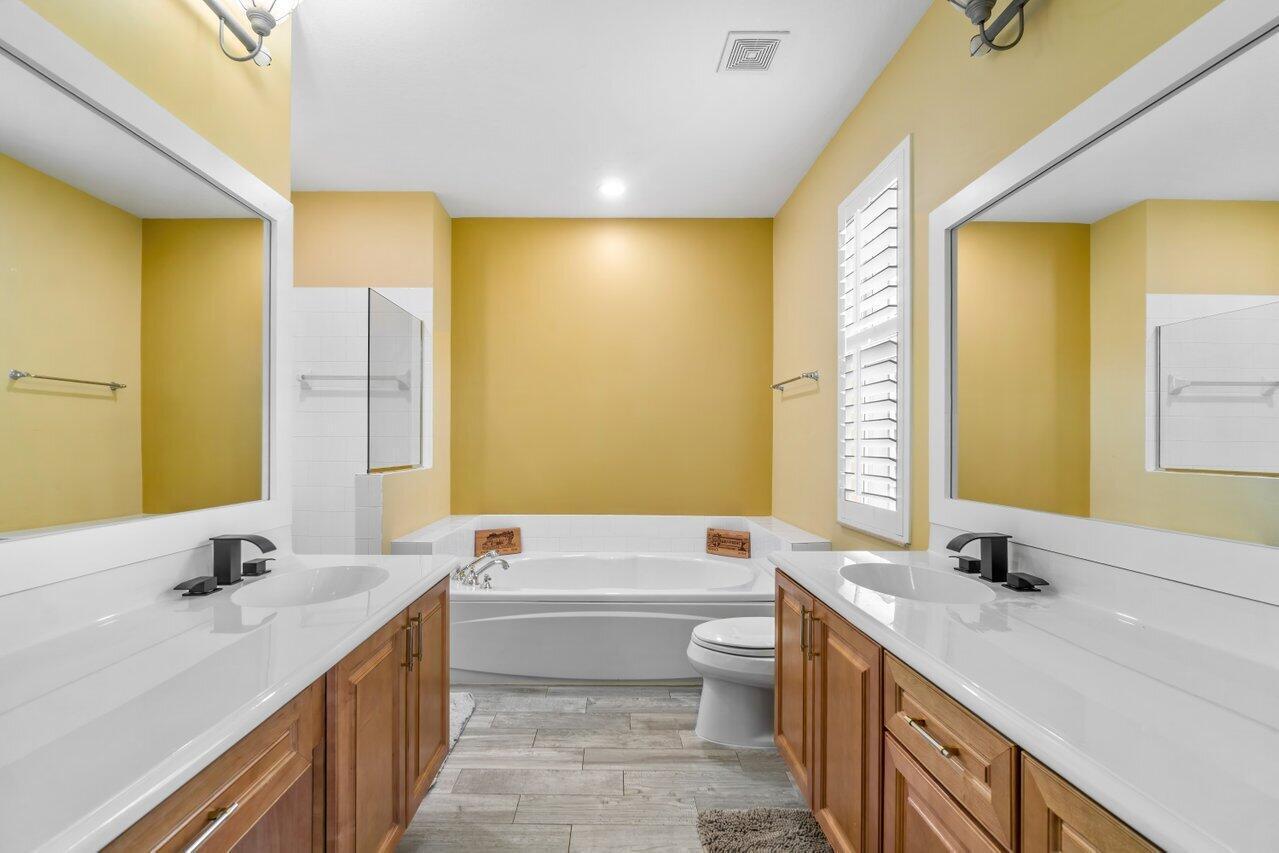 3805 Northwest 5th Terrace Boca Raton, FL 33431 - Photo 19 of 30 a bathroom with a double vanity sink toilet mirror and bathtub