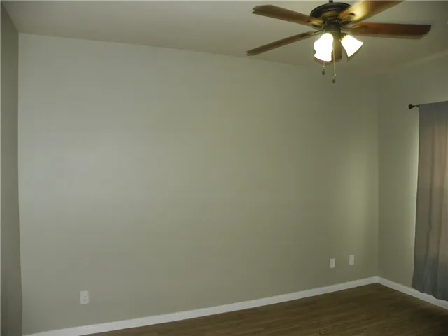 a view of a small space with wooden floor and a fan
