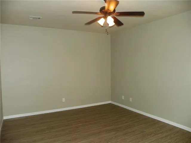 an empty room with wooden floor and fan