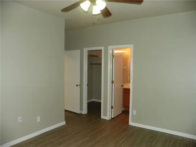 an empty room with wooden floor and a ceiling fan