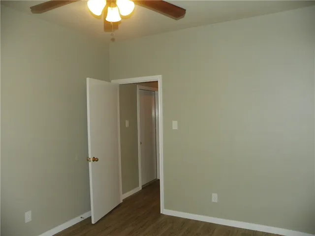 an empty room with wooden floor and fan