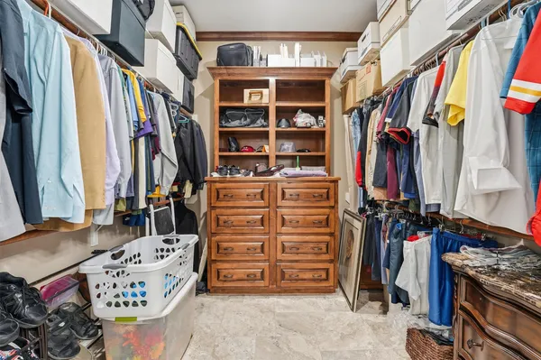 a view of walk in closet with clothes and shoes