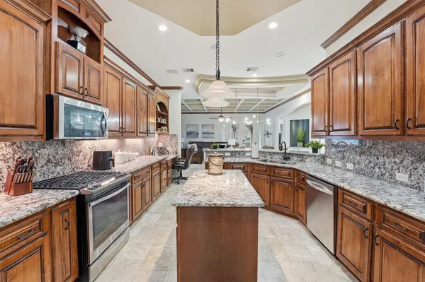 a large kitchen with stainless steel appliances granite countertop a stove and large cabinets