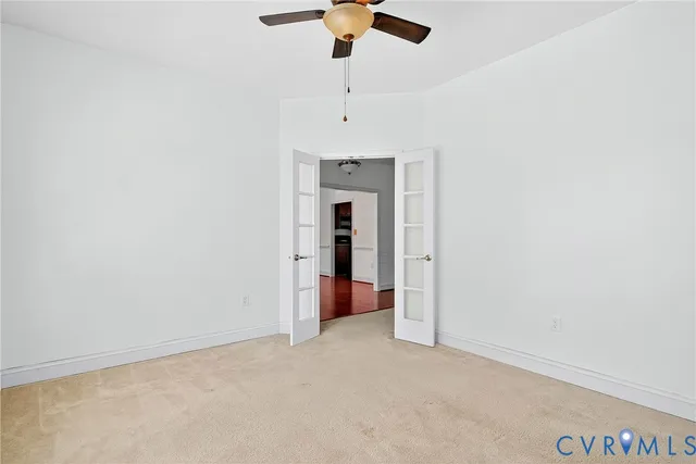 an empty room with a ceiling fan and carpet