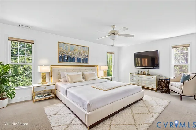 a bedroom with a large bed couch and two windows