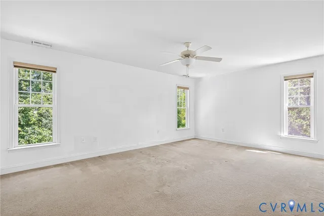 an empty room with windows and ceiling fan view