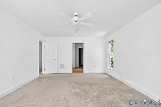 a view of an empty room with chandelier fan